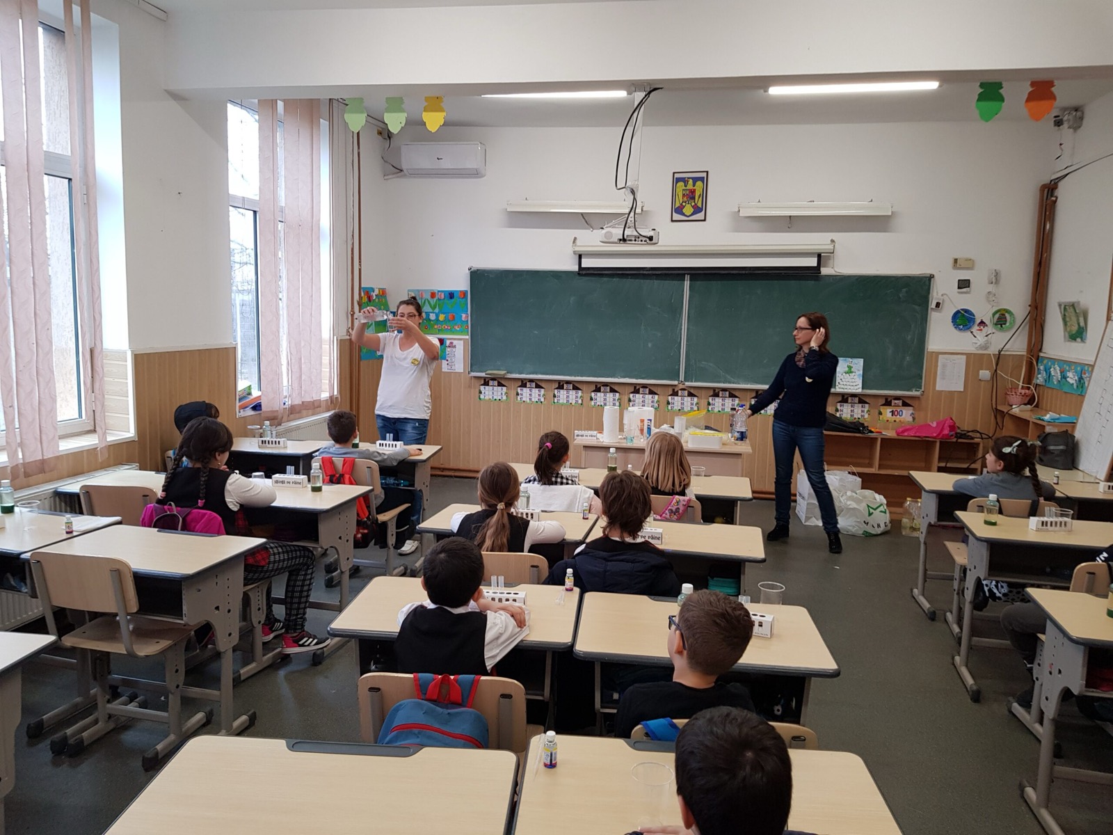 Profesoară care face un experiment în fața unei clase