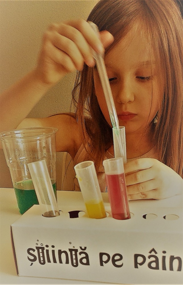 Fetiță care pune colorant cu pipeta în eprubete